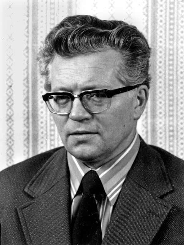 Frontalfoto eines Mannes mit Hornbrille und Anzug.