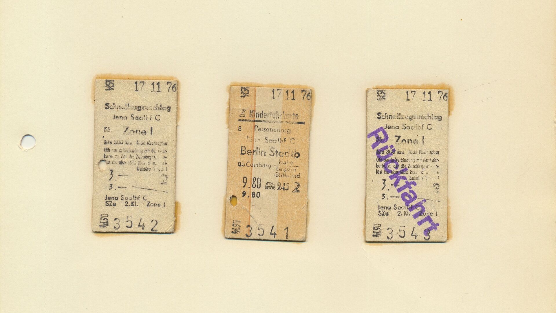Ein Blatt, auf dem drei Fahrkarten nebeneeinander aufgeklebt sind. Auf der rechten steht in lila Schrift "Rückfahrt".