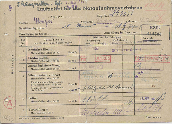 Der Zettel ist mit Stempeln und Unterschriften der zahlreichen Stellen übersäht, die Flüchtende im Notaufnahmelager Berlin-Marienfelde zu besuchen hatten.