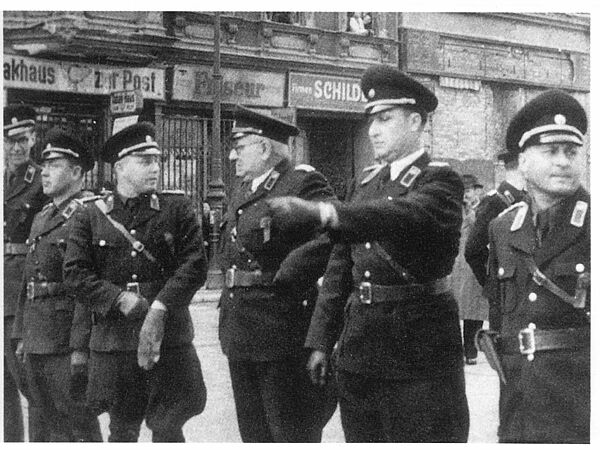 Fünf Männer in Polizeiuniformen stehen nebeneinander in einer Reihe auf einer Straße. 