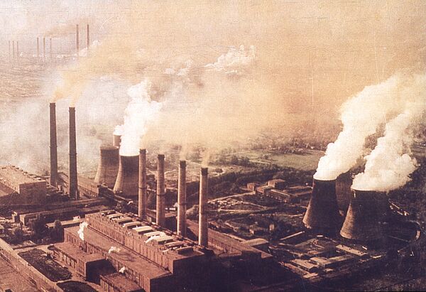 Luftaufnahme einer großen, in starke Abgas- und Dampf gehüllten Industrieanlage.