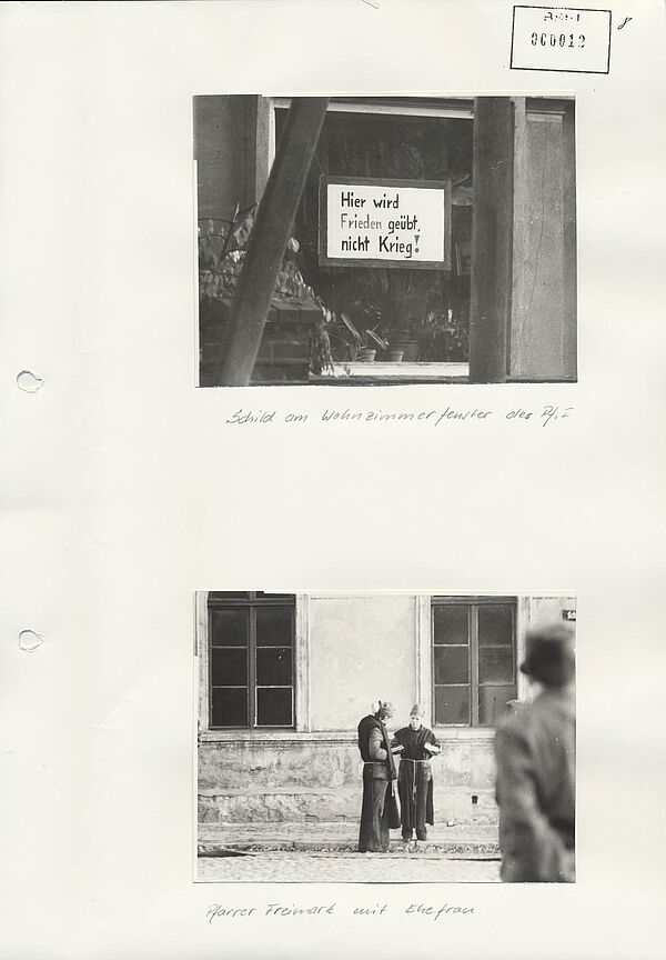Seite aus einer Stasi-Akte, auf der zwei Fotos aufgeklebt sind. Das Obere zeigt ein Schild an einem Fenster auf dem "Hier wird Frieden geübt, nicht Krieg!" mit der Bildunterschrift "Schild am Wohnzimmerfenster Pf. F". Das untere zeigt zwei Personen vor einem Haus stehend mit der Bildunterschrift "Pfarrer Freimark mit Ehefrau"