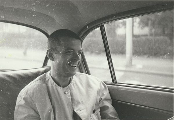 Foto eines lachenden Mannes, der auf der Rückbank eines Autos sitzt.