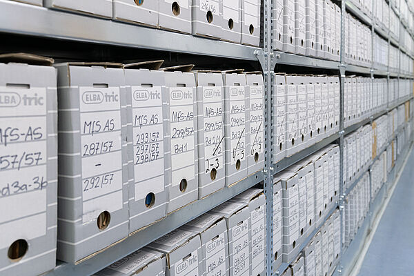 Zu sehen sind Schwerlastregale, die mit zahlreichen Pappboxen gefüllt sind, in denen Papier zu sehen ist. Beschriftet sind sie mit "MfS AS" und ansteigenden Nummern.