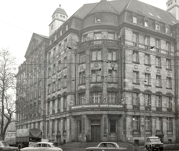 Blick auf das Gebäude der BV Leipzig, der sogenannten Runden Ecke, einem Geschäftshaus vom Anfang des 20. Jahrhunderts. Über dem Eingangsportal ein Banner mit Bezug zur Sowjetunion: "Waffenbrüder - Klassenbrüder - vereint unbesiegbar".