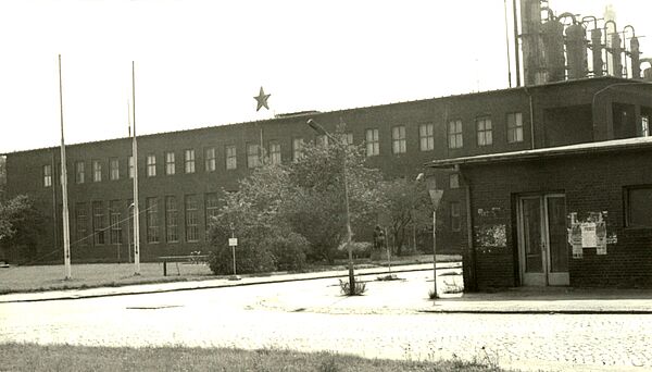 Schwarz-Weiß-Foto eines zweigeschössigen Industriebaus, über dem ein Stern angebracht ist.