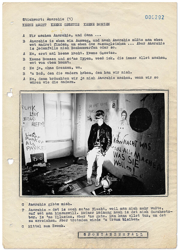 Seite aus der Broschüre "Erinnerung an eine Jugendbewegung: Punk" von Gilbert Radulovic (heute Furian), Quelle: Privatbesitz Gilbert Furian Textdokument, in der Mitte ist ein aufgeklebtes Bild einer Person in nietenbesteckter Lederjacke, auf den Wänden im Hintergrund stehen Parolen wie "Lieber Punker als Pauker" oder "Keiner macht was er soll - Alle machen was sie wollen".