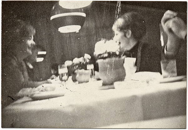 Heimliche Aufnahme von Gästen im Restaurant "Malmö" im Rostocker Interhotel "Warnow", Anfang der 1980er Jahre  Quelle: BArch, MfS, BV Rostock, Abt. VIII, Nr. 24, Teil 3, Bl. 285 Unscharfes, anscheinend heimlich aufgenommenes Schwarz-Weiß-Foto zweier weiblicher Personen die an einem Tisch sitzen und sich lachend unterhalten. Am rechten Bildrand sind die zwei Hände einer weiteren Person zu erkennen..