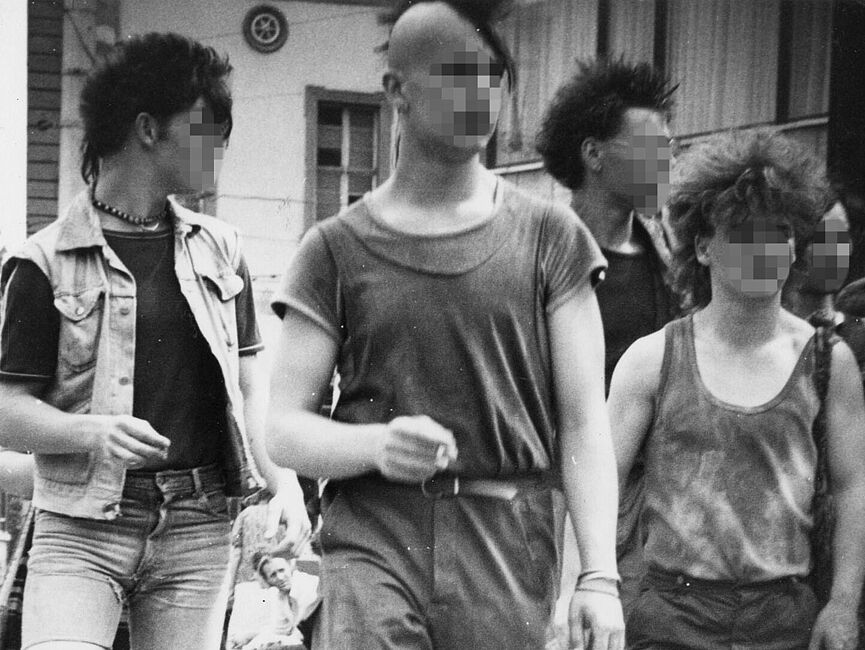 Schwarz-Weiß-Foto einer Gruppe Jugendlicher im Punk-Look, im Hintergrund Häuser.
