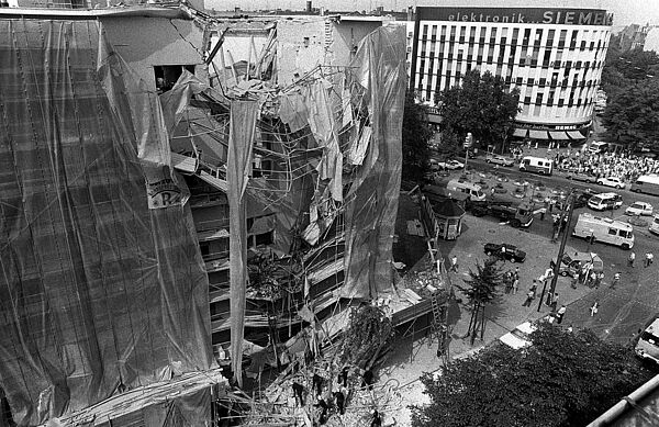 Das Maison de France am Kurfürstendamm in West-Berlin, Sitz des französischen Kulturinstituts sowie des französischen Generalkonsulats, nach dem Bombenanschlag vom 25. August 1983 Blick vom Dach des in der Uhlandstraße gegenüberliegenden Hauses auf das stark beschädigte Maison de France. Feuerwehrmänner klettern über die Trümmer auf dem Bürgersteig, Einsatzkräfte der Polizei sind in der Umgebung des Gebäudes zu sehen.