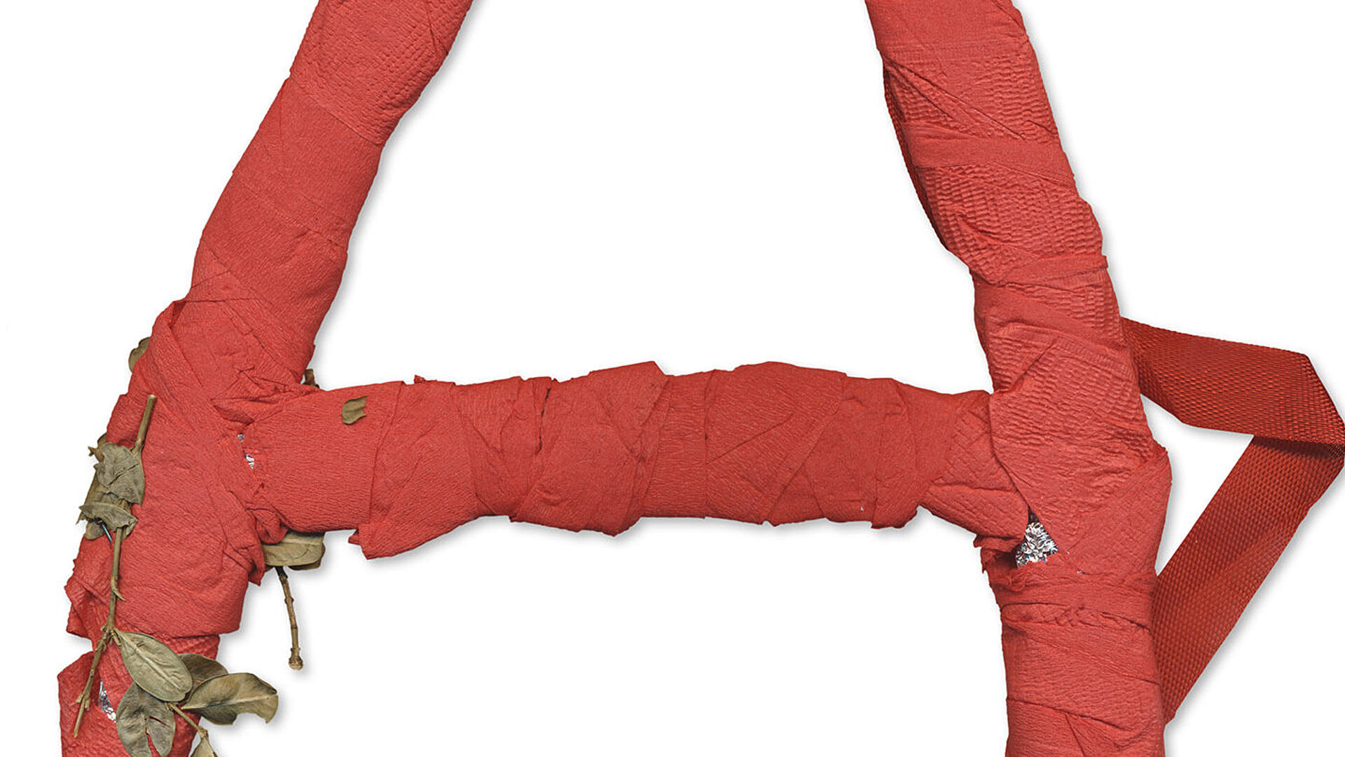 Ein aus rotem Krepppapier gebasteltes "A", verziert mit getrockneten Blättern.