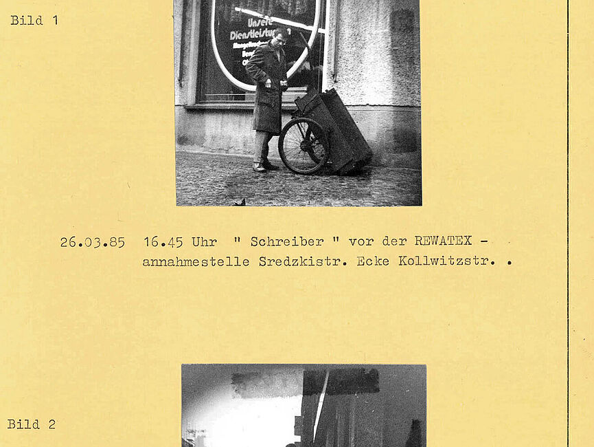 Bildbericht der Observation Radulovics durch Mitarbeiter der HA VIII am 26. März 1985 Zwei auf einem gelben Blatt aufgeklebte Fotos mit Unterschriften. Das obere Bild zeigt einen Mann im Mantel mit einem Holzwagen, der vor einem Schaufenster steht. Das untere Bild zeigt selbigen Mann von hinten, der den Holzwagen zieht, auf dem ein zusammengerollter Teppich liegt.