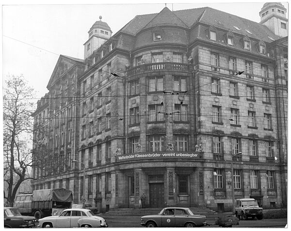 Stasi-BV Leipzig am Dittrichring, 1985. Blick auf das Gebäude der BV Leipzig, der sogenannten Runden Ecke, einem Geschäftshaus vom Anfang des 20. Jahrhunderts. Über dem Eingangsportal ein Banner mit Bezug zur Sowjetunion: "Waffenbrüder - Klassenbrüder - vereint unbesiegbar".