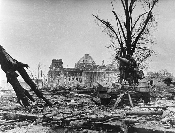 Foto des zerstörten Reichstagsgebäudes in Berlin inmitten einer Trümmerlandschaft