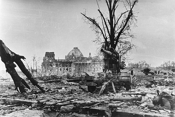 Foto des zerstörten Reichstagsgebäudes in Berlin inmitten einer Trümmerlandschaft